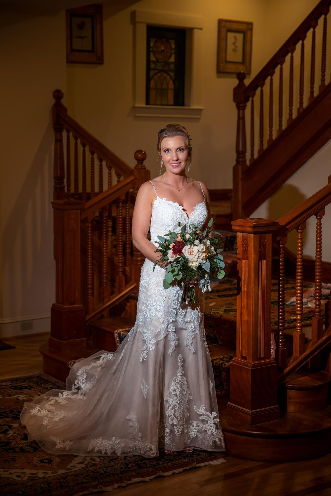 A country bride in a wedding dress standing on a staircase.