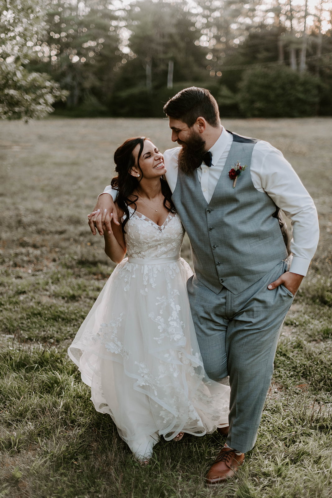 A country bride and groom hugging in a field at sunset.