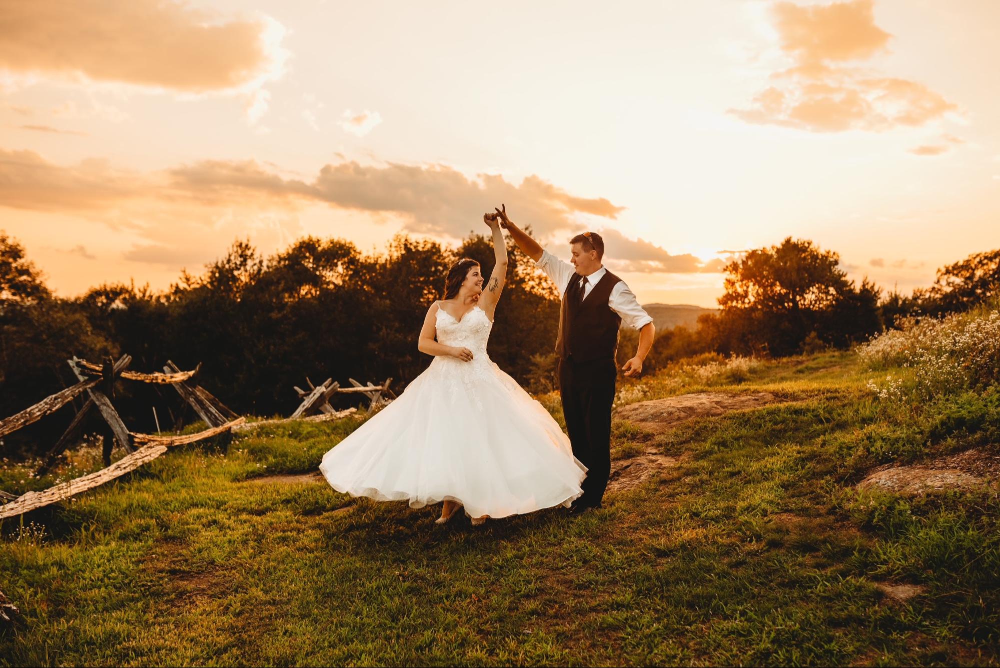 A picturesque scene of a country bride and groom standing on a hill at sunset.
