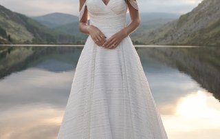 A Siva bride in a white wedding dress standing by a lake.