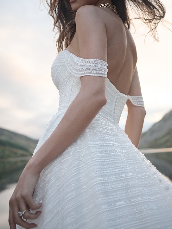 The back of a woman in a Siva wedding dress posing by a lake.