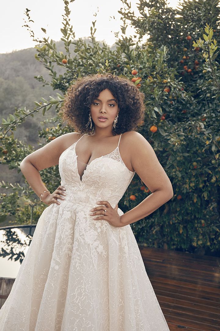 A plus size woman in a wedding dress posing on a deck.