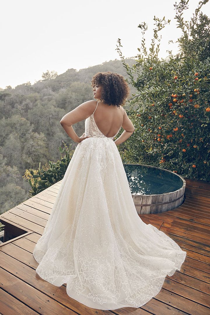 A woman is standing on a wooden deck in a wedding dress.